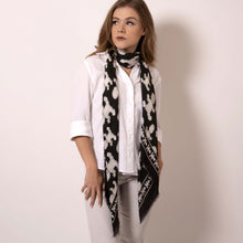 Load image into Gallery viewer,  Artskul&#39;s Baby Pop Large Square Cashmere Blend Scarf can be styled with a choker drape effect.  This black and white scarf is lusciously soft and easy to style in so many different ways. This scarf is made in Italy from the most luxurious fabric with hand fringed edging.  ärtskül’s remixed houndstooth pattern captivates the eye while paying homage to the classic print with a twist of the unexpected. 